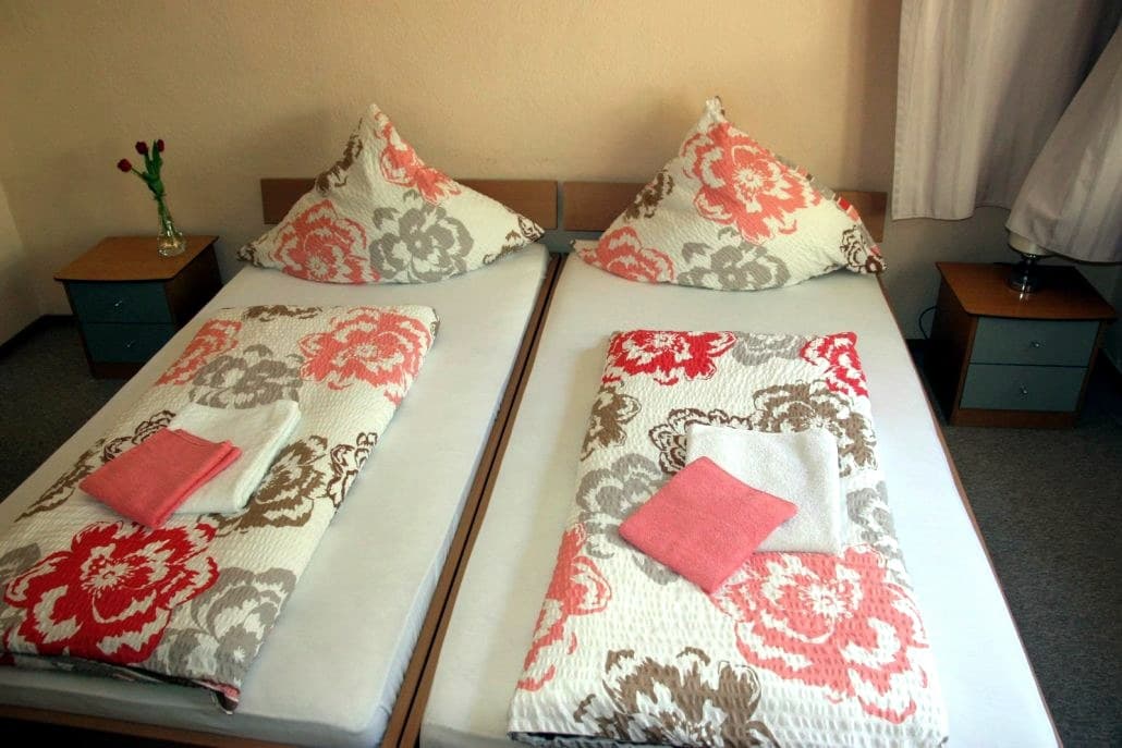 Doppelzimmer mit zwei Betten, geblümten Decken und Handtüchern